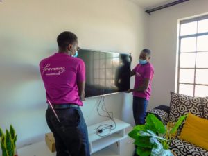 Two Nellion's staff moving a TV